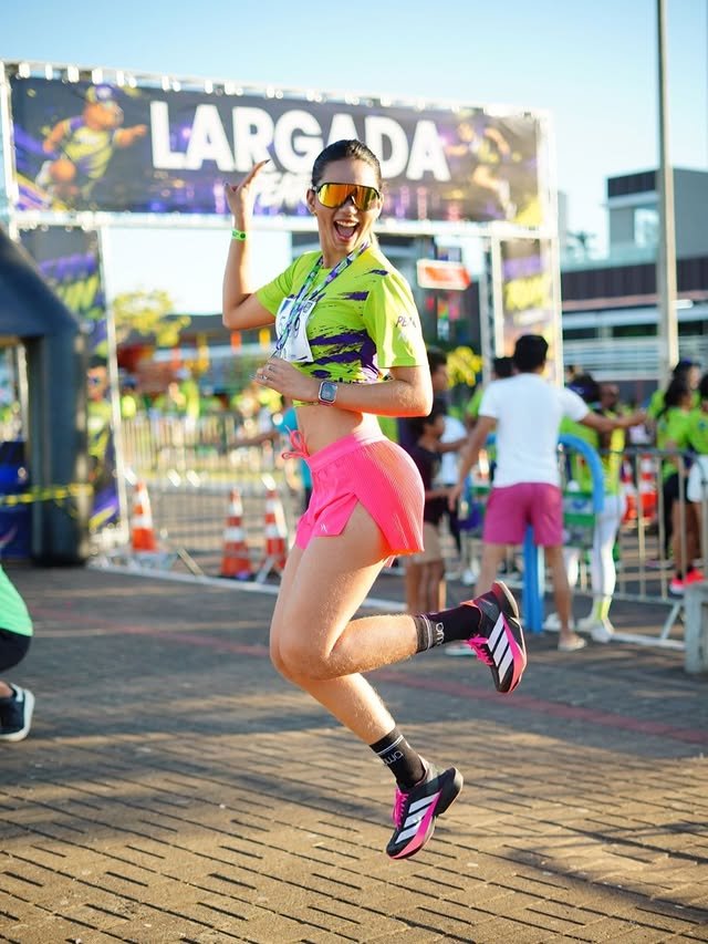Atleta salta de alegria com a medalha da Peara Run em frente ao pórtico de largada