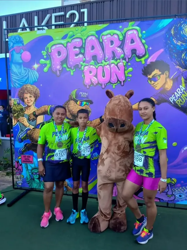 Mãe e filhos com medalhas posam ao lado do mascote capivara da Peara Run