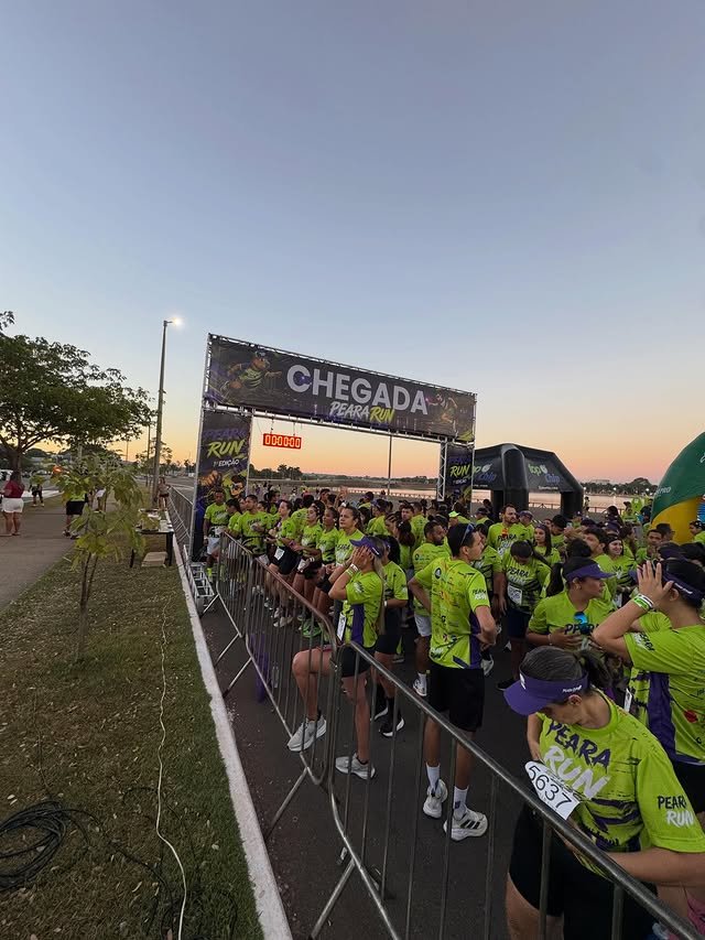 Multidão de corredores concentrada no pórtico de chegada da Peara Run ao amanhecer, na Via Lago