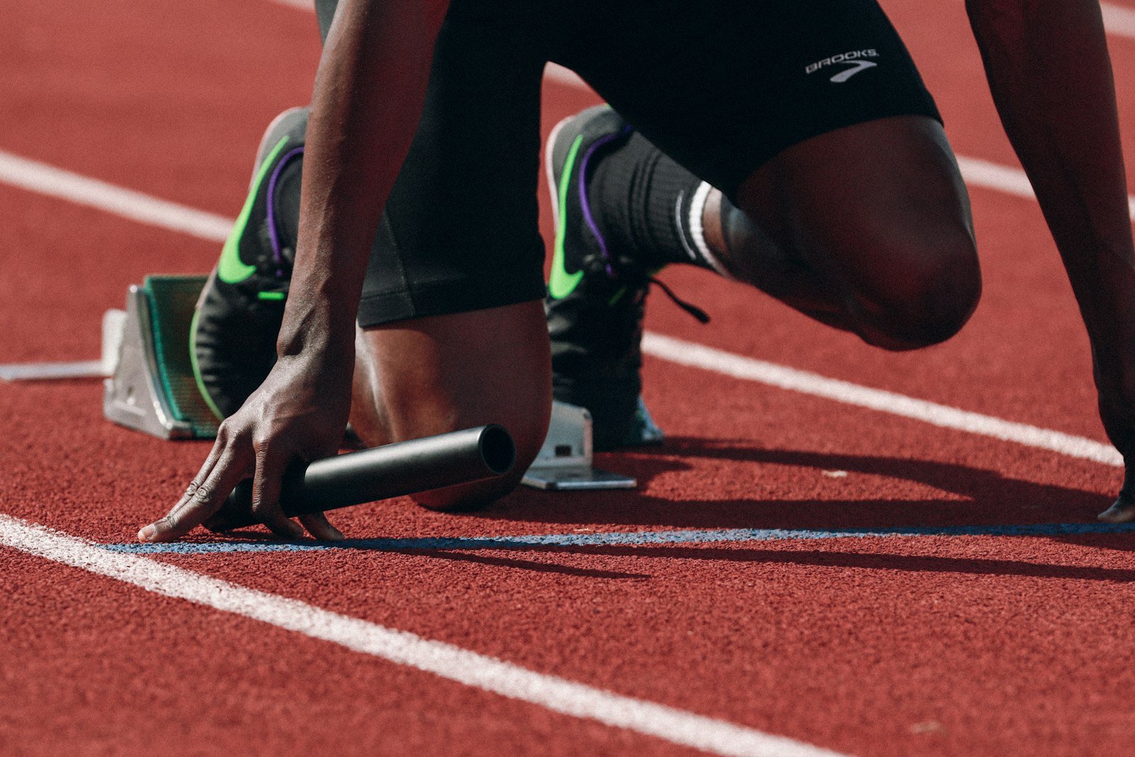 Atleta posicionado no bloco de largada em uma pista de corrida